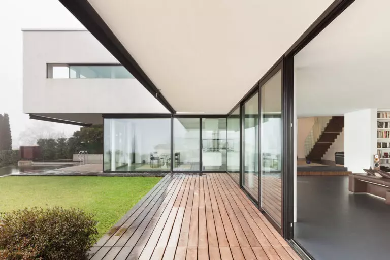 Salon contemporain avec grande baie vitrée donnant sur un jardin, conçu par Arca Menuiseries.