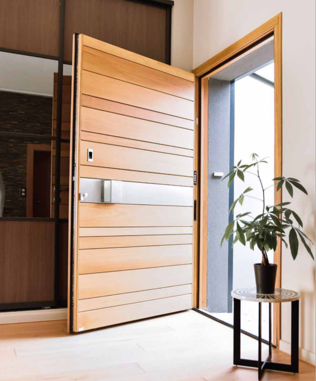 Porte d'entrée avec encadrement en bois naturel, conçue par Arca Menuiseries.