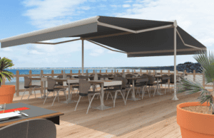 Store banne motorisé installé par Arca Menuiseries pour une terrasse avec vue panoramique sur la mer.