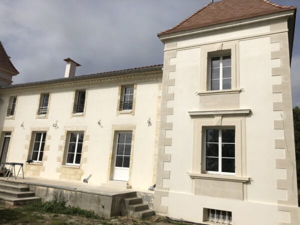 Façade d’une maison en pierre avec menuiseries blanches