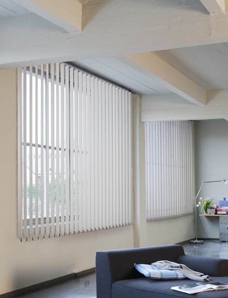 Rideaux verticaux blancs sur mesure pour baie vitrée, installés par Arca Menuiseries.