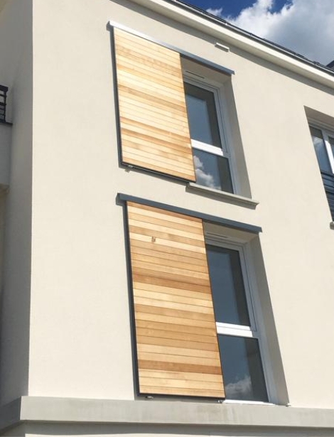 Volets coulissant en bois naturel sur mesure installés par Arca Menuiseries.